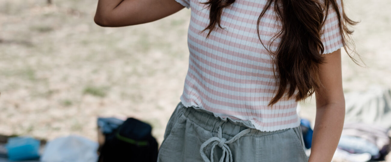 A young woman smiles as she holds a vintage portable speaker aloft